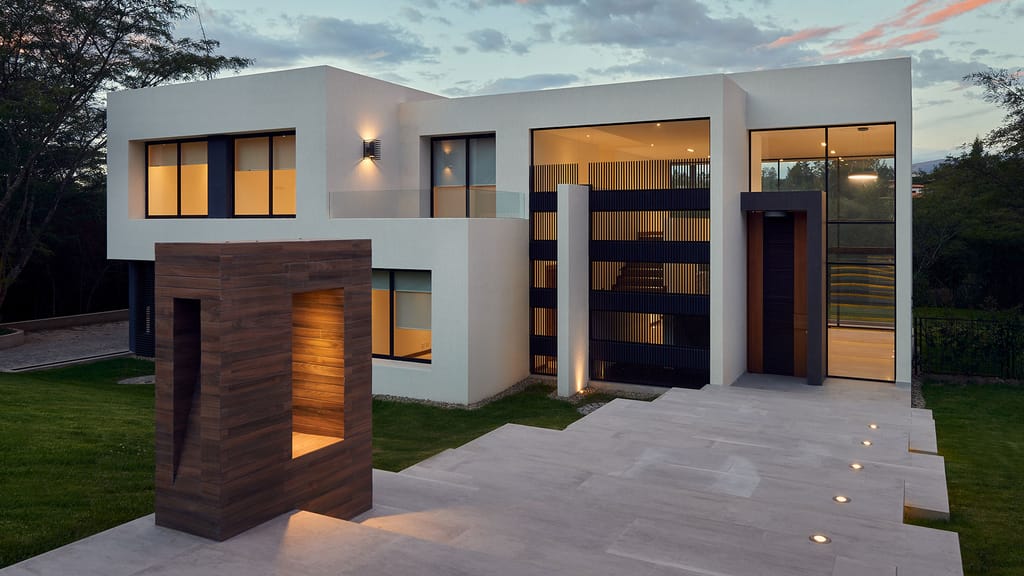 Modernes Wohnhaus mit großflächigen Fenster- und Türelementen in der Abenddämmerung